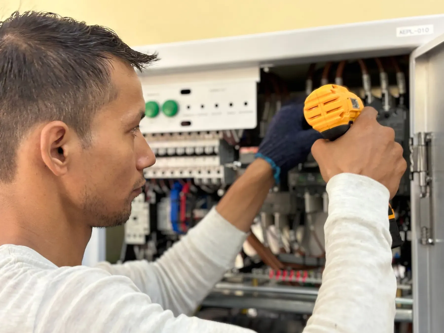 An electrician working inside an open residential breaker panel
